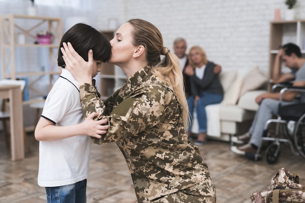 La donna in uniforme mimetica bacia suo figlio.