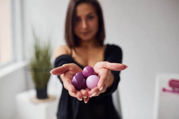 La donna in vestiti sexy neri mostra le palle vaginali e gli strumenti di imbuilding nella stanza.