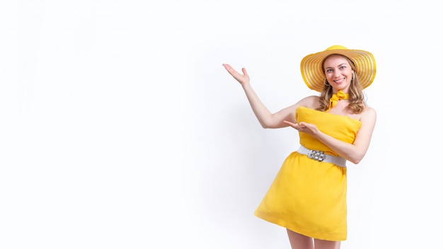 La donna in vestito e cappello gialli dal cuscino sorride e mostra le mani