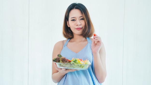 La donna incinta asiatica sta mangiando l&#39;insalata