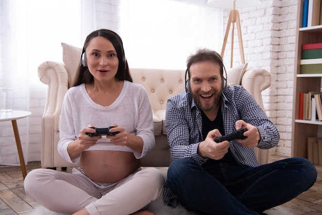 La donna incinta e l&#39;uomo sta giocando sul joystick