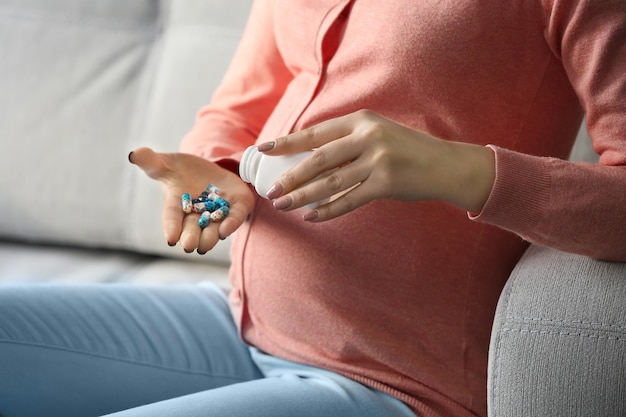 La donna incinta prende le pillole che si siedono sul sofà all'interno