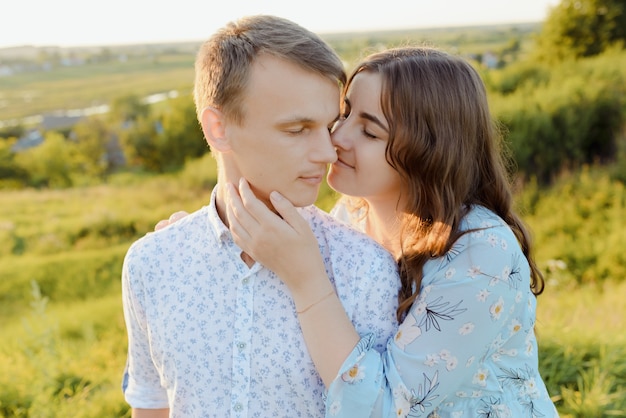 La donna incinta sta baciando con il marito al tramonto. Famiglia felice