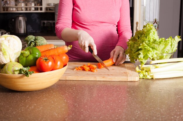 La donna incinta sta cucinando piatti in cucina