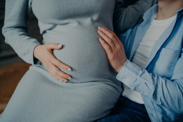 La donna incinta tocca la pancia attende le pose del bambino sulle mani dei mariti