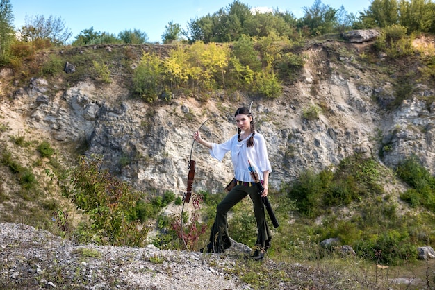 La donna indiana posa in una natura che circonda con freccia e arco. ritratto di donna cacciatrice