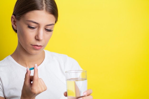 La donna infelice tiene la pillola e un bicchiere d'acqua