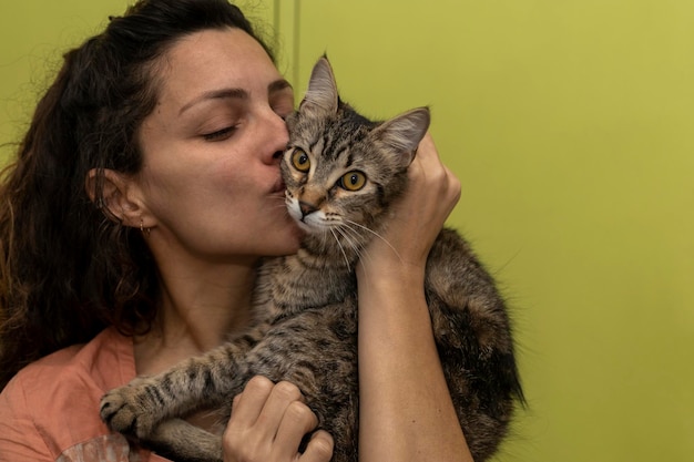 La donna latinoamericana tiene in braccio e gioca affettuosamente con il suo gatto