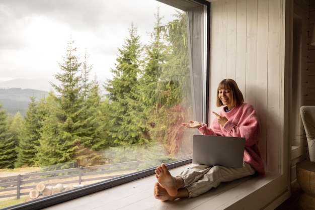 La donna lavora al computer portatile a casa in montagna