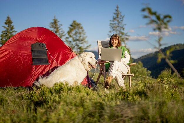 La donna lavora al computer portatile al campeggio in montagna