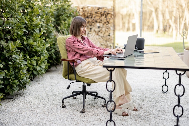 La donna lavora al computer portatile online nel giardino all'aperto