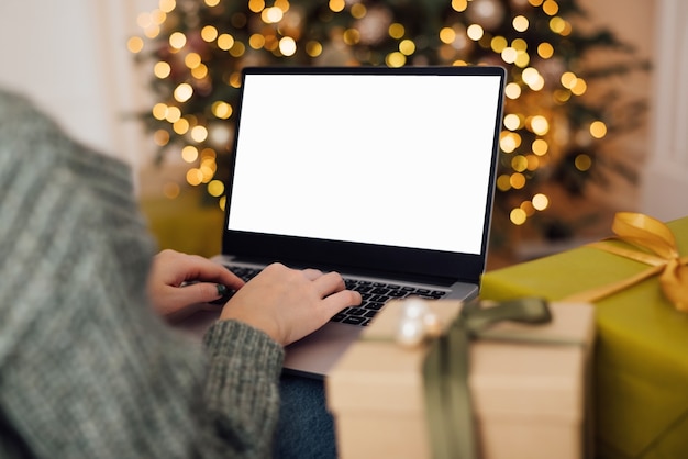 La donna lavora all'interno della casa del computer portatile decorato per la celebrazione di Natale con l'albero di Natale