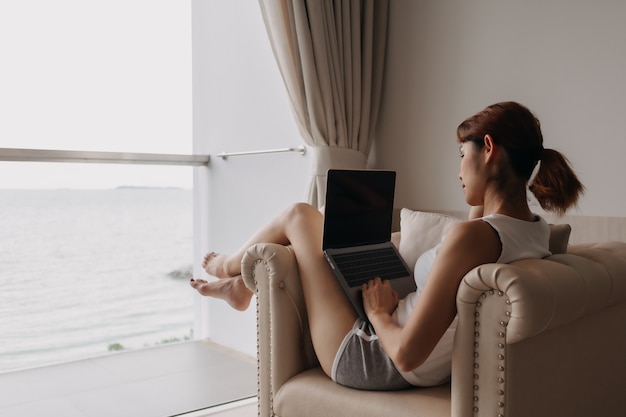 La donna lavora e si rilassa con il portatile sul divano concetto di lavoro da hotel