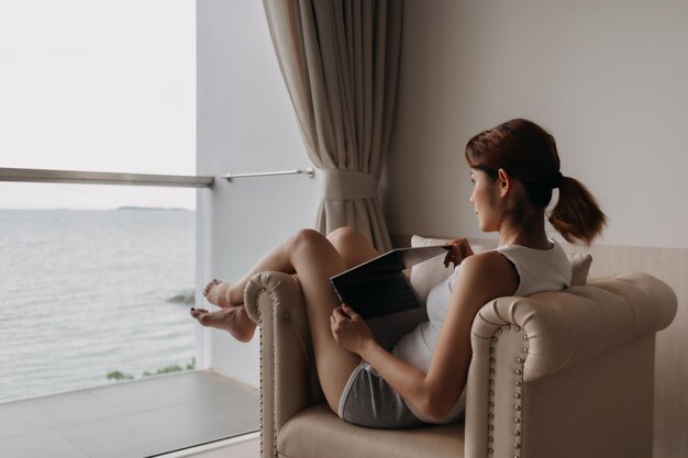 La donna lavora e si rilassa con il portatile sul divano concetto di lavoro da hotel