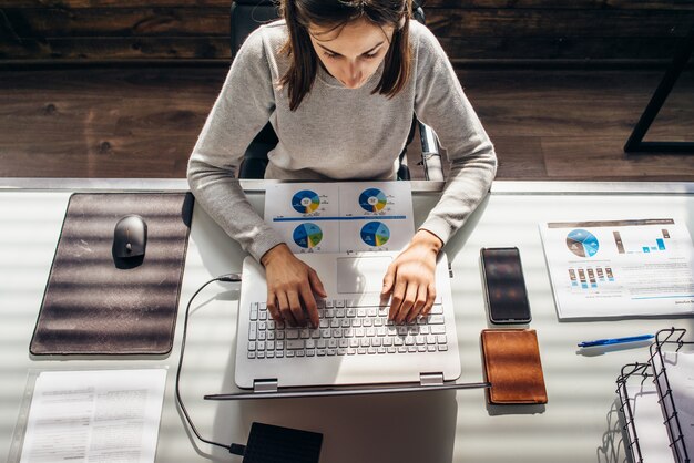 La donna lavora in ufficio con il computer portatile al tavolo di lavoro.