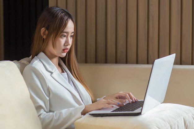 La donna lavoratrice professionale asiatica sta sedendosi e usando il computer portatile del computer portatile nel lavoro da casa