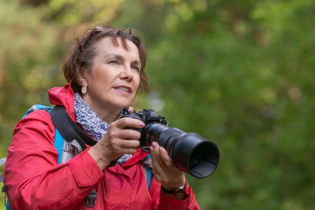 La donna maggiore fa una foto nella foresta