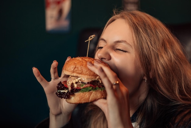 La donna mangia l'hamburger nella caffetteria