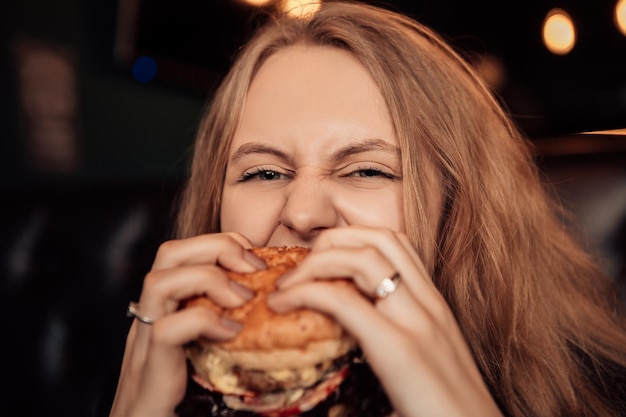 La donna mangia l'hamburger nella caffetteria