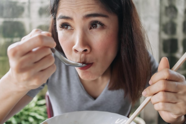 La donna mangia le tagliatelle piccanti con le bacchette nella via locale