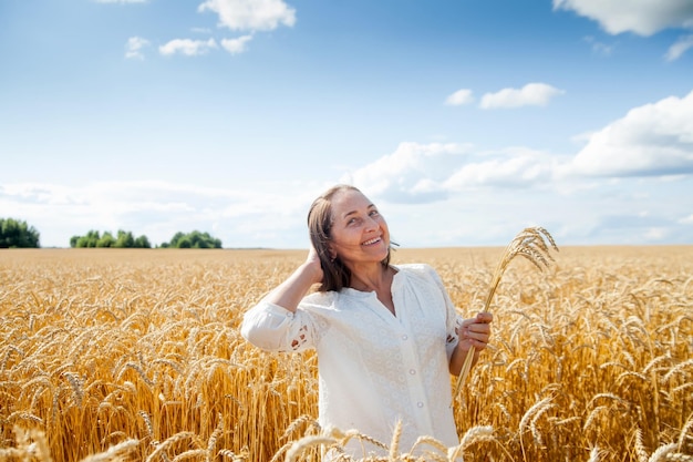 La donna matura di bellezza sola cammina sul photoxDxA orizzontale del campo di grano