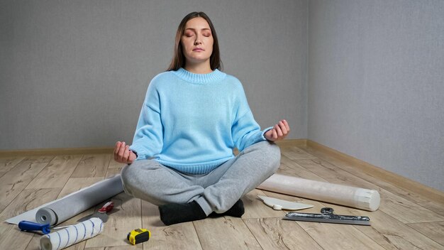 La donna medita seduta sul parquet tra i materiali da costruzione