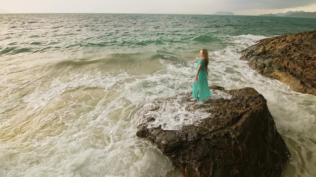 La donna medita si rilassa su una collina di scogliera rocciosa in un mare nuvoloso di pioggia mattutina tempestosa