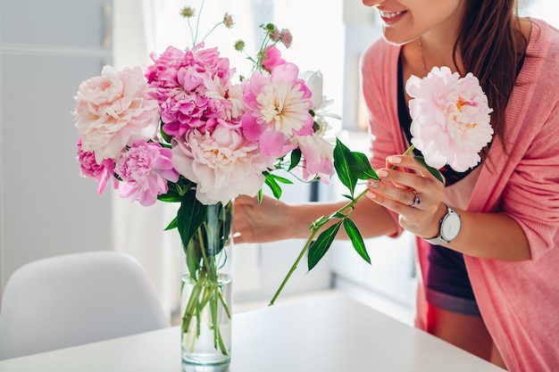 La donna mette i fiori di peonie in vaso.