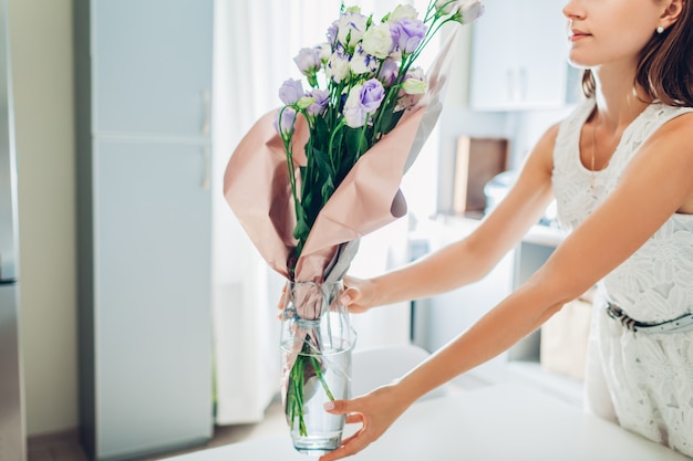 La donna mette il vaso con i fiori. Casalinga che si prende cura dell'intimità in cucina. Cucina moderna