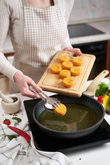 La donna mette le palline di formaggio nella padella con olio da cucina caldo