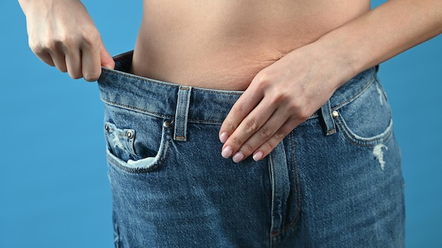 La donna mostra che ha perso peso e che i suoi vecchi jeans hanno uno sfondo blu troppo grande con spazio per la copia
