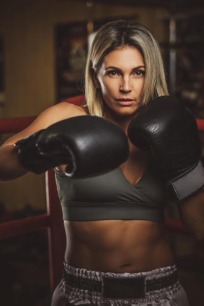 La donna muscolare concentrata ha il suo allenamento di boxe indossando guanti da boxe.