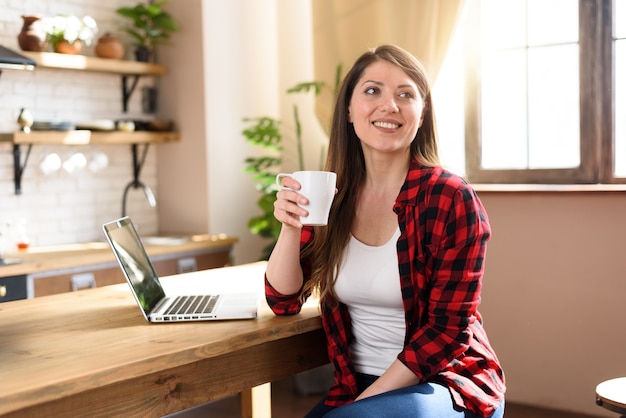 La donna naviga in Internet con il suo laptop con uno schermo bianco, lavora a casa come smart working