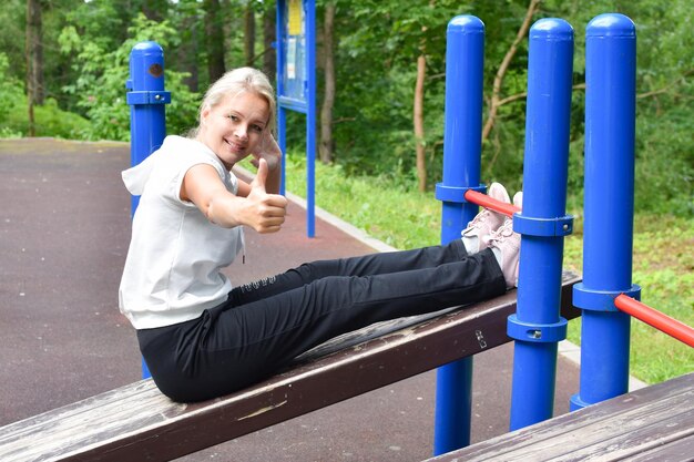 la donna nel parco è impegnata nella ginnastica ragazza sulla ginnastica con barra orizzontale all'esterno