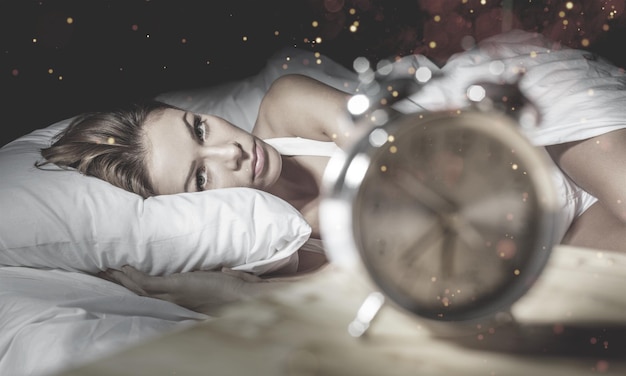 La donna nel suo letto con l'insonnia e gli incubi non riesce a dormire aspettando che la sua sveglia suoni