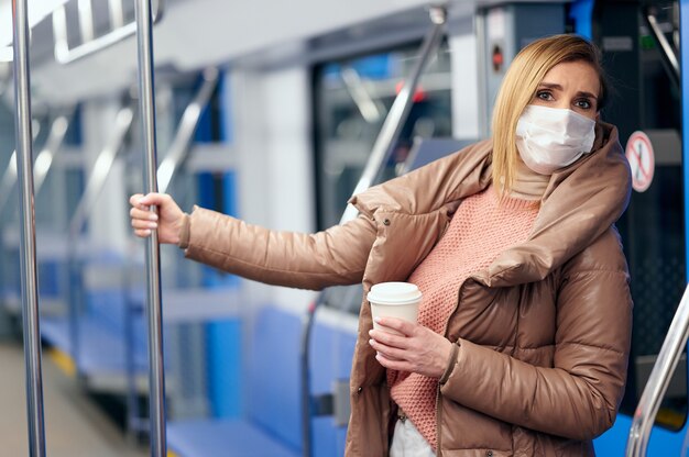 La donna nella stazione della metropolitana che indossa una maschera chirurgica igienica protettiva sul viso previene il rischio di coronavirus