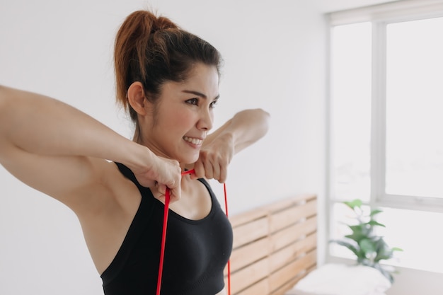 La donna nello sport indossa l'allenamento di fila verticale della fascia di resistenza in camera da letto