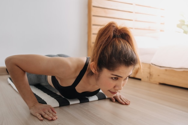 La donna nello sport indossa l'allenamento push up della fascia di resistenza nella sua stanza