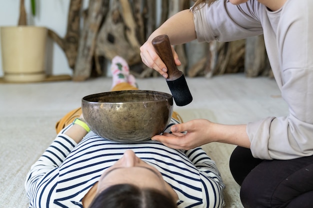 La donna ottiene un massaggio sonoro energetico con la terapia delle campane tibetane a casa