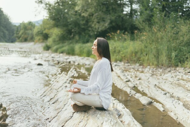 La donna pacifica sta facendo la meditazione del mantra vicino al fiume