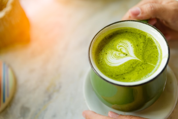 La donna passa a holding tazza di tè verde caldo a forma di cuore.