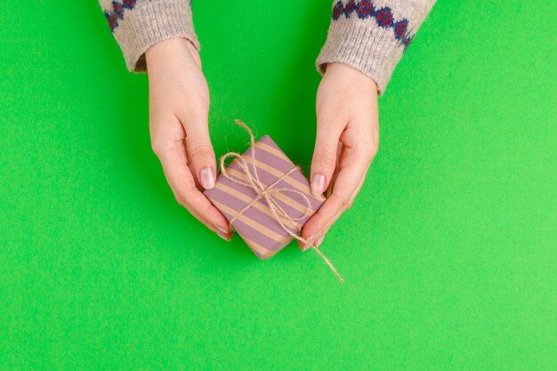 La donna passa il contenitore di regalo della tenuta su fondo verde