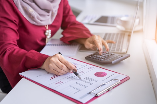 La donna passa il lavoro con il calcolatore circa la pianificazione finanziaria personale al caffè.