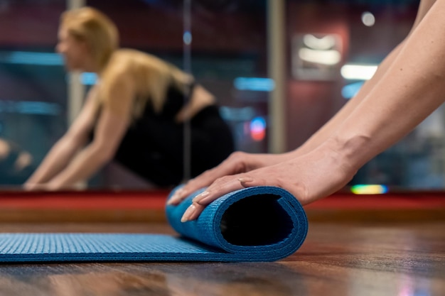 La donna passa il tappetino da yoga in studio dopo aver praticato l'allenamento yoga