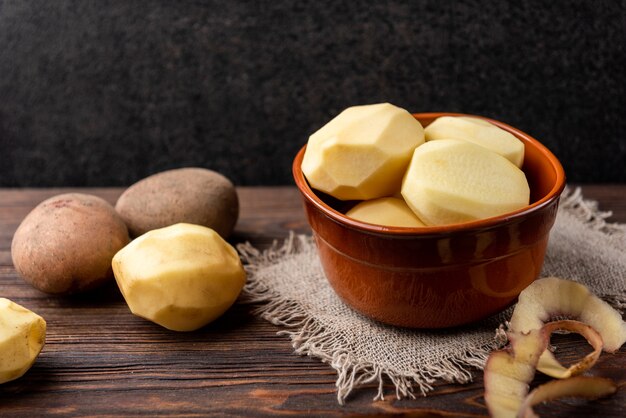 La donna passa la buccia di patate. Patate pulite su una superficie di legno. Riparare il cibo per cucinare.