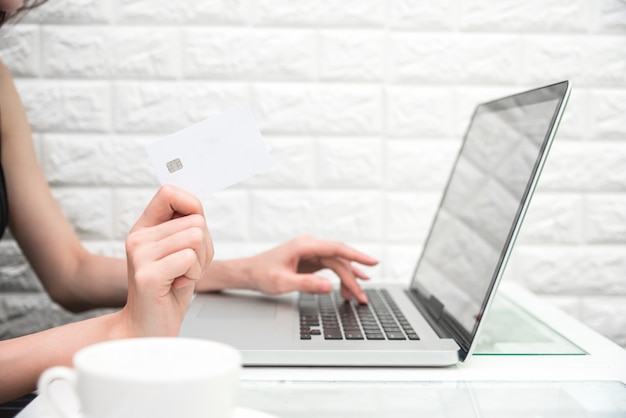 La donna passa la carta di credito della tenuta per acquisto online o ordina il prodotto da Internet quando per mezzo del computer portatile