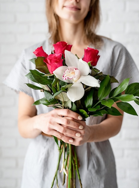 La donna passa la tenuta del mazzo delle rose e dell'orchidea che celebra la festa