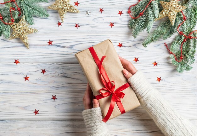 La donna passa la tenuta del regalo di Natale avvolto con la decorazione delle stelle dell'albero di abete e degli sparklins