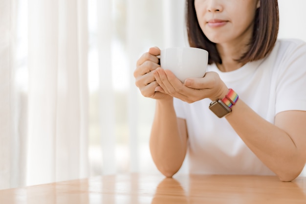 La donna passa la tenuta della tazza di caffè bianco