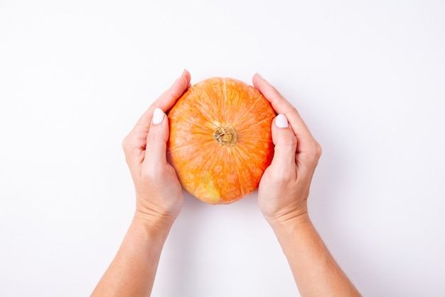 La donna passa la tenuta della zucca arancione piccola su bianco